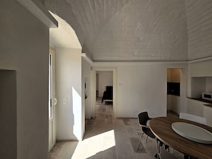 Una habitación amplia con una mesa de comedor, sillas y una zona de cocina con microondas.