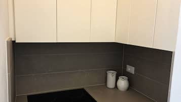 A modern kitchen with white cabinets, dark backsplash, and two black induction cooktops.
