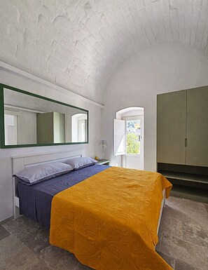 Ein Schlafzimmer mit Bett, Kleiderschrank, Spiegel und einer Tür, die auf einen Balkon führt.