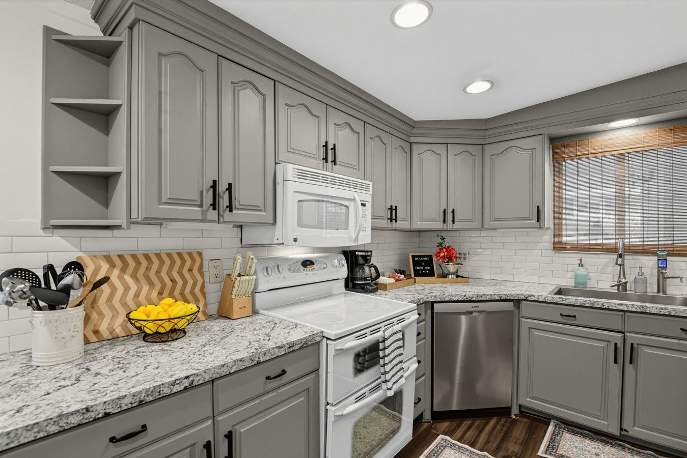 A kitchen with grey cabinets, a white stove, and a dishwasher.