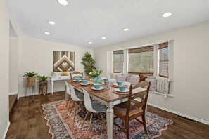 A dining area with a wooden table set for four, surrounded by white chairs. - Spacious Taylorsville Home w Finished Basement! (Taylorsville)