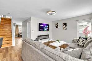 A modern living room with a sofa set, a coffee table, and a flat-screen TV mounted on the wall. - 4BR Family Home • Ideal for Insurance & Work Stays (Lake in the Hills)