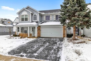 A two-story house with a garage, a covered porch, and a snow-covered driveway. - 4BR Family Home • Ideal for Insurance & Work Stays (Lake in the Hills)