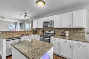 A kitchen with white cabinets, granite countertops, a stainless steel stove, and a microwave. - 4BR Family Home • Ideal for Insurance & Work Stays (Lake in the Hills)