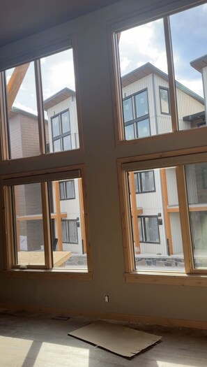 Una habitación con ventanas amplias, un enchufe a la vista y materiales de construcción en el suelo.