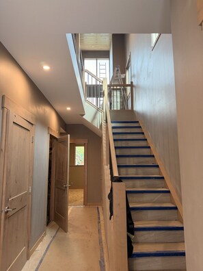A multi-level interior with a staircase, wooden doors, and a view to the upper floor. - Luxury Meets Location | Hot Tub and Firepit (Canmore)