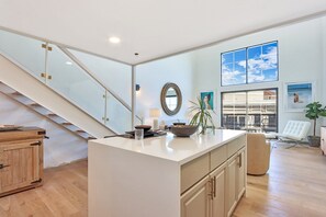Une cuisine spacieuse dotée d’un îlot central, de meubles en bois et d’un escalier menant à un niveau supérieur.