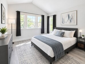 Quarto com cama, mesa de cabeceira, luminária, janela com cortinas, uma planta e um quadro na parede.