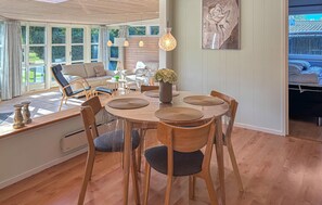 A dining area with a round table, wooden chairs, and a vase of flowers. - 3 bedroom cozy home in Væggerløse (Væggerløse)