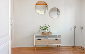 A minimalist room with a white console table, two wall-mounted mirrors, a potted plant, and a floor lamp. - 3 bedroom cozy home in Væggerløse (Væggerløse)