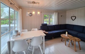 A room with a white table, chairs, a dark blue sofa, a wooden stool, and a heart-shaped decoration on the wall. - Stunning home in Melsomvik with harbor view (Melsomvik)