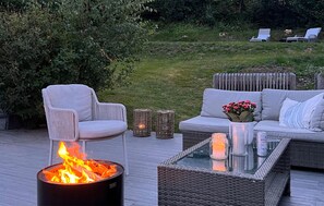 An outdoor seating area with a fire pit, wicker furniture, and a grassy lawn in the background. - Amazing home in Melsomvik with harbor view (Melsomvik)