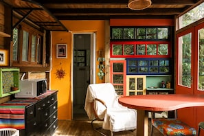 A room with a wooden ceiling, a white chair, a table, and a colorful wall with multiple windows.