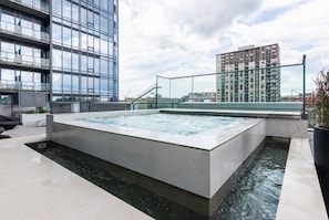 A rooftop pool with a glass enclosure, surrounded by modern buildings. - Modern Downtown Montreal 1-Bedroom Condo with Pool & Rooftop (Montréal)