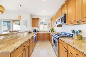 A modern kitchen with granite countertops, wooden cabinets, a stainless steel stove, and a microwave. - La Jolla Beach House -  Walk to Windansea, EV Charger (San Diego)