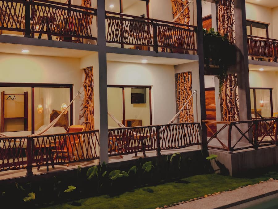 A multi-story hotel with balconies, a swimming pool, and a well-maintained lawn.