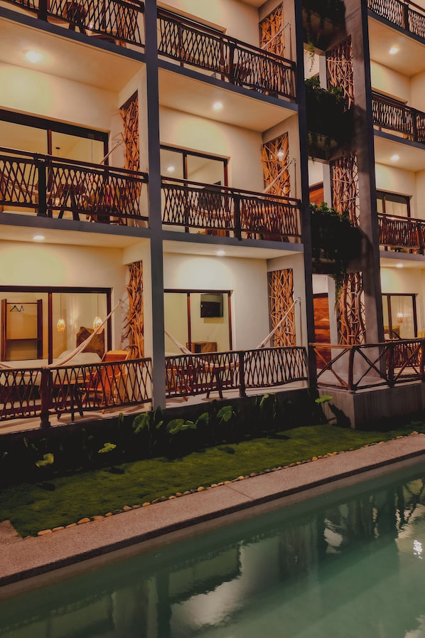 A multi-story hotel with balconies, a swimming pool, and a well-maintained lawn.