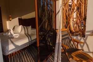 A room with a bed, a chair, and a woven structure.