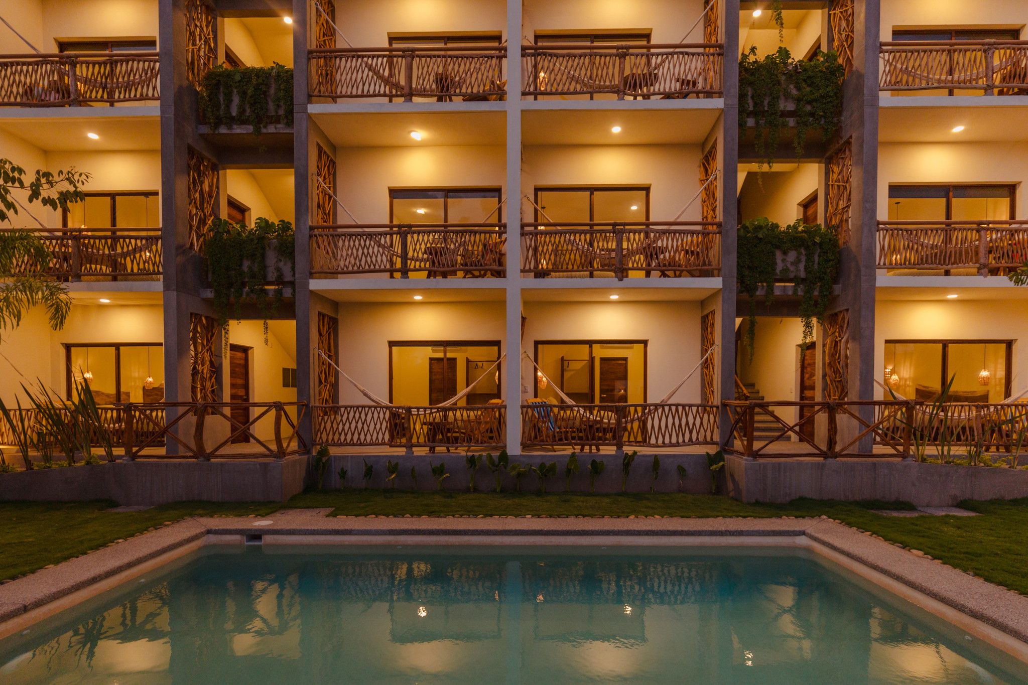 A multi-story hotel with balconies, a swimming pool, and a well-lit facade.