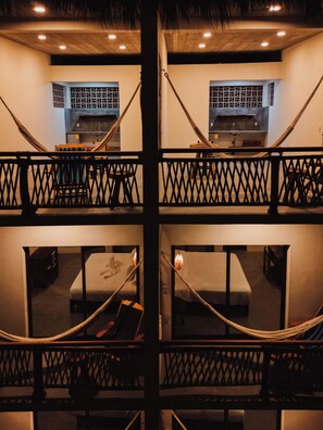 A multi-level hotel room with a balcony, hammocks, and a kitchen area.