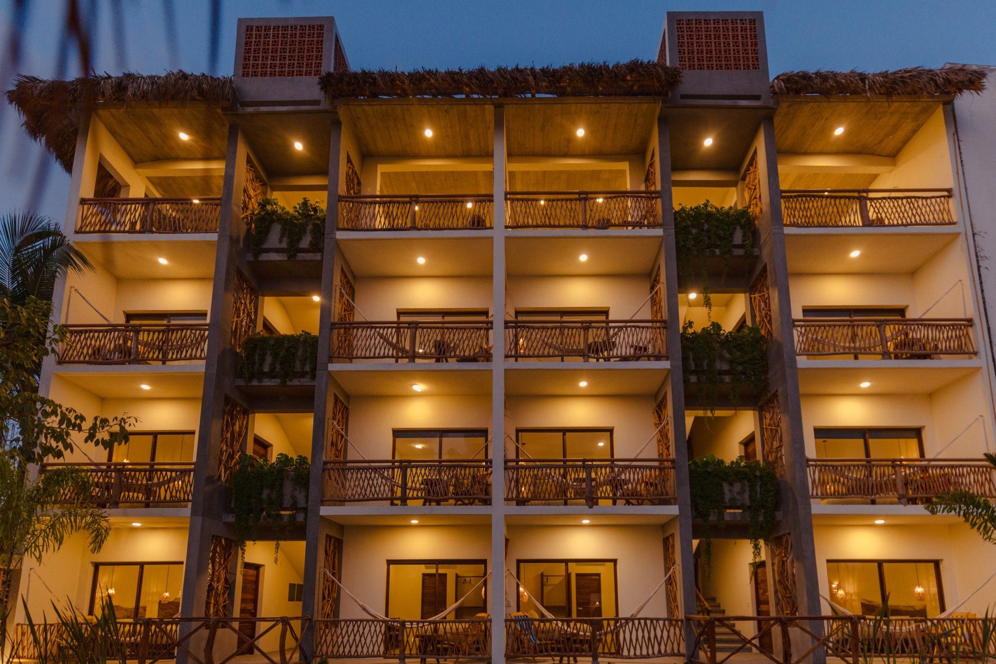 A multi-story hotel with balconies, each with a wooden railing and potted plants.