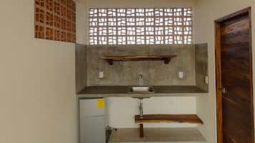 A compact kitchen with a built-in sink, a small refrigerator, and a wooden door.