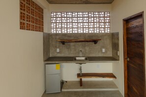 Cocina compacta con pileta integrada, un refrigerador pequeño y una puerta de madera.