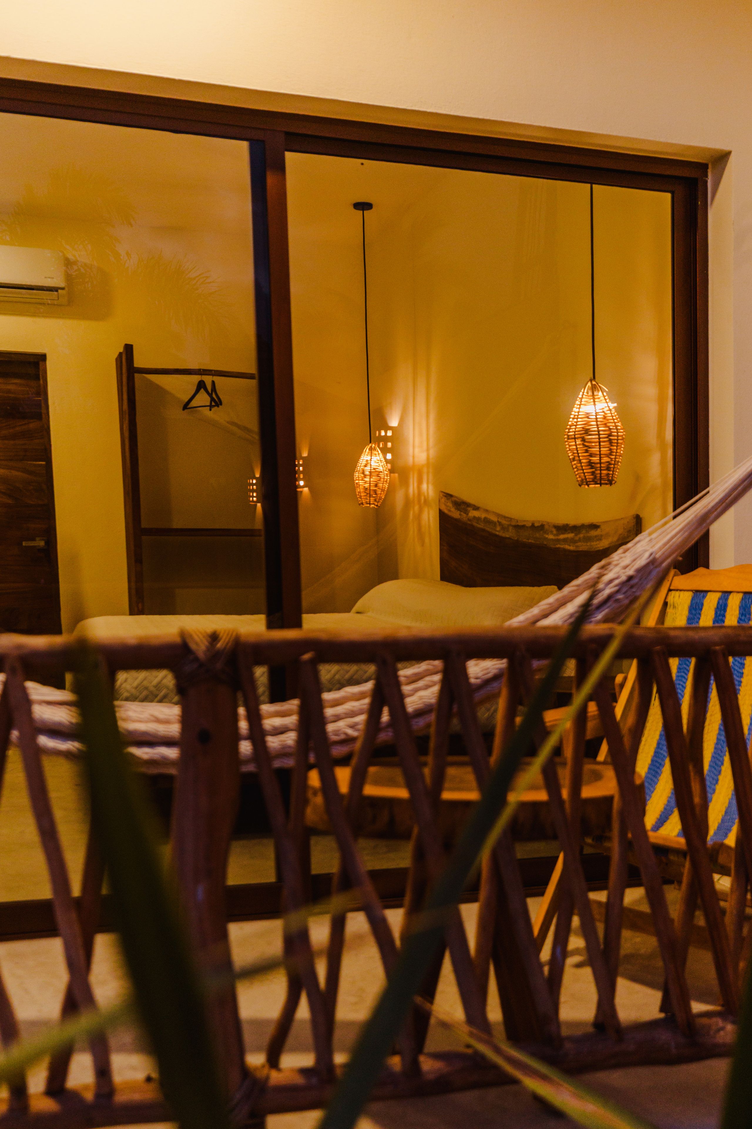 Una habitación con una cama, una silla colgante y un gran ventanal corredera.