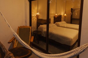 Una habitación con dos camas, una silla y una hamaca.