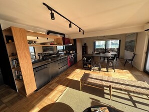 A modern kitchen with a central island, wooden cabinetry, and a dining area with a view. - Vrbo Property (Las Condes)