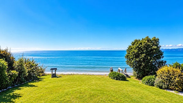 A grassy area with a bench and a gazebo overlooking a clear blue sea. - Pakawau Beach - Ratrace Retreat (Pākawau)