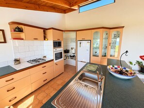 Een keuken met een gasfornuis, oven, magnetron en een spoelbak met een moderne kraan.