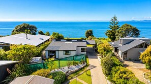 A coastal residential area with houses, a clear blue sky, and a view of the sea. - Pakawau Beach - Ratrace Retreat (Pākawau)