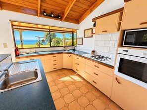 Une cuisine avec vue sur la mer, une cuisinière à gaz, un four à micro-ondes et un évier.
