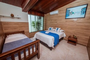 Ein Hotelzimmer mit zwei Betten, einer Holzbalkendecke, einem großen Fenster und einem Gemälde an der Wand.