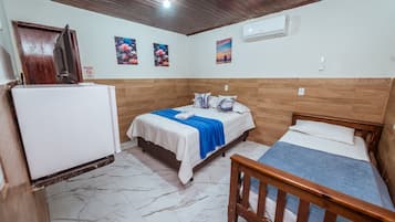 A room with two beds, a wooden ceiling, a white air conditioner, and a refrigerator.