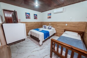 A room with two beds, a wooden ceiling, a white air conditioner, and a refrigerator.