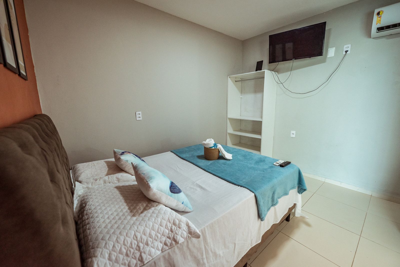 Una habitación de hotel con cama, armario, televisor y aire acondicionado.