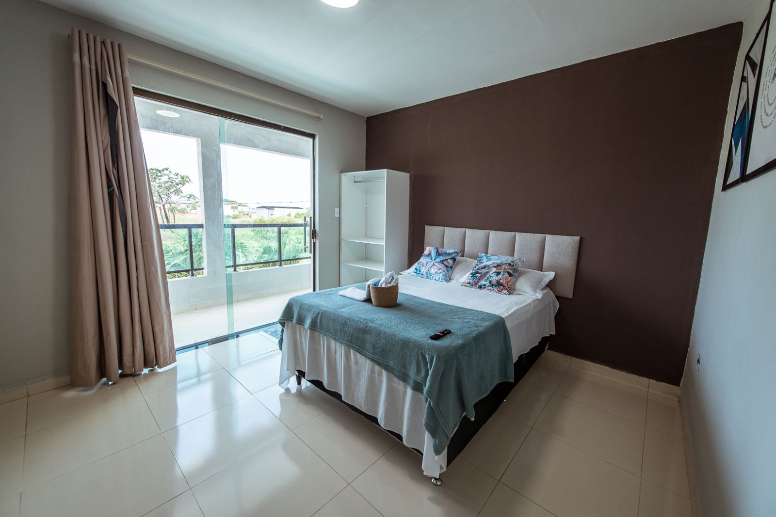 Un dormitorio con cama, armario y vista a través de un ventanal.