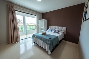 A bedroom with a bed, a wardrobe, and a view through a glass door.