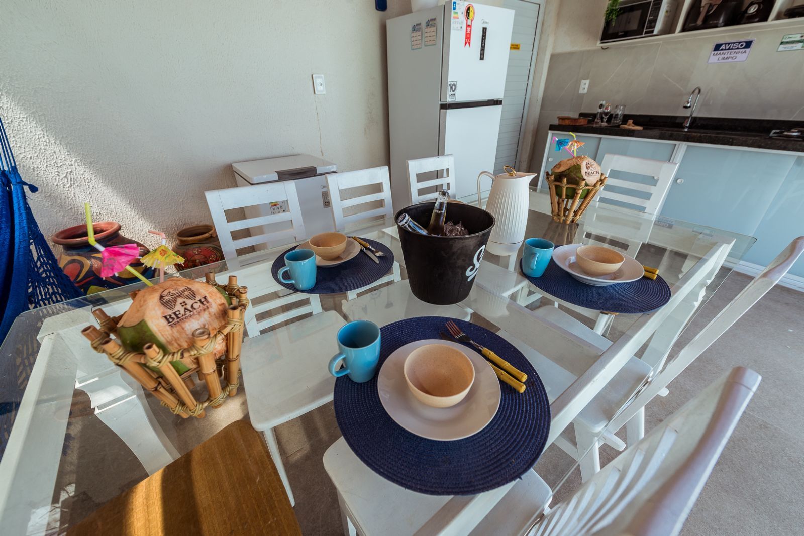 Un comedor con sillas blancas, una mesa de vidrio y un cubo negro.