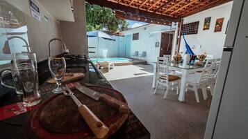 A kitchen area with a bar counter, a dining table with chairs, and a pool visible in the background.