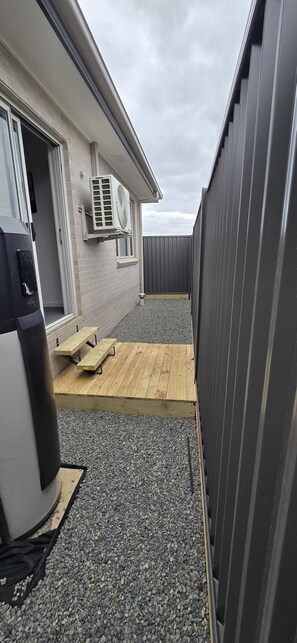 A covered outdoor area with a wooden deck, a grill, and a barbecue. - Coast, Canopy & City: Cozy 2-bedroom Home (Gilead)