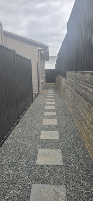 A narrow pathway with stepping stones leading to a building entrance. - Coast, Canopy & City: Cozy 2-bedroom Home (Gilead)