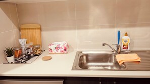 A kitchen with a stainless steel sink, a dish rack, a plant, and various kitchen items on the counter. - Coast, Canopy & City: Cozy 2-bedroom Home (Gilead)