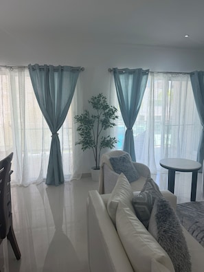 A modern living room with a sofa, a small round table, and a potted plant. - An exquisite an exceptional, 5 star resorts style condominium complex (Punta Cana)