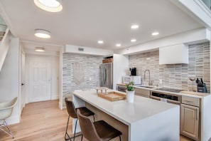 Una cocina moderna con una isla central, electrodomésticos de acero inoxidable y un salpicadero blanco.