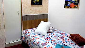 A bedroom with a bed, a door, and two paintings on the wall.