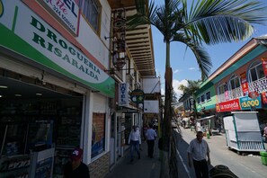 A street view with a hotel named 'Hotel Juancell Technology' and a sign for 'Droguería Risada' on the left. - Hotel Arte  (SANTA ROSA DE CABAL)