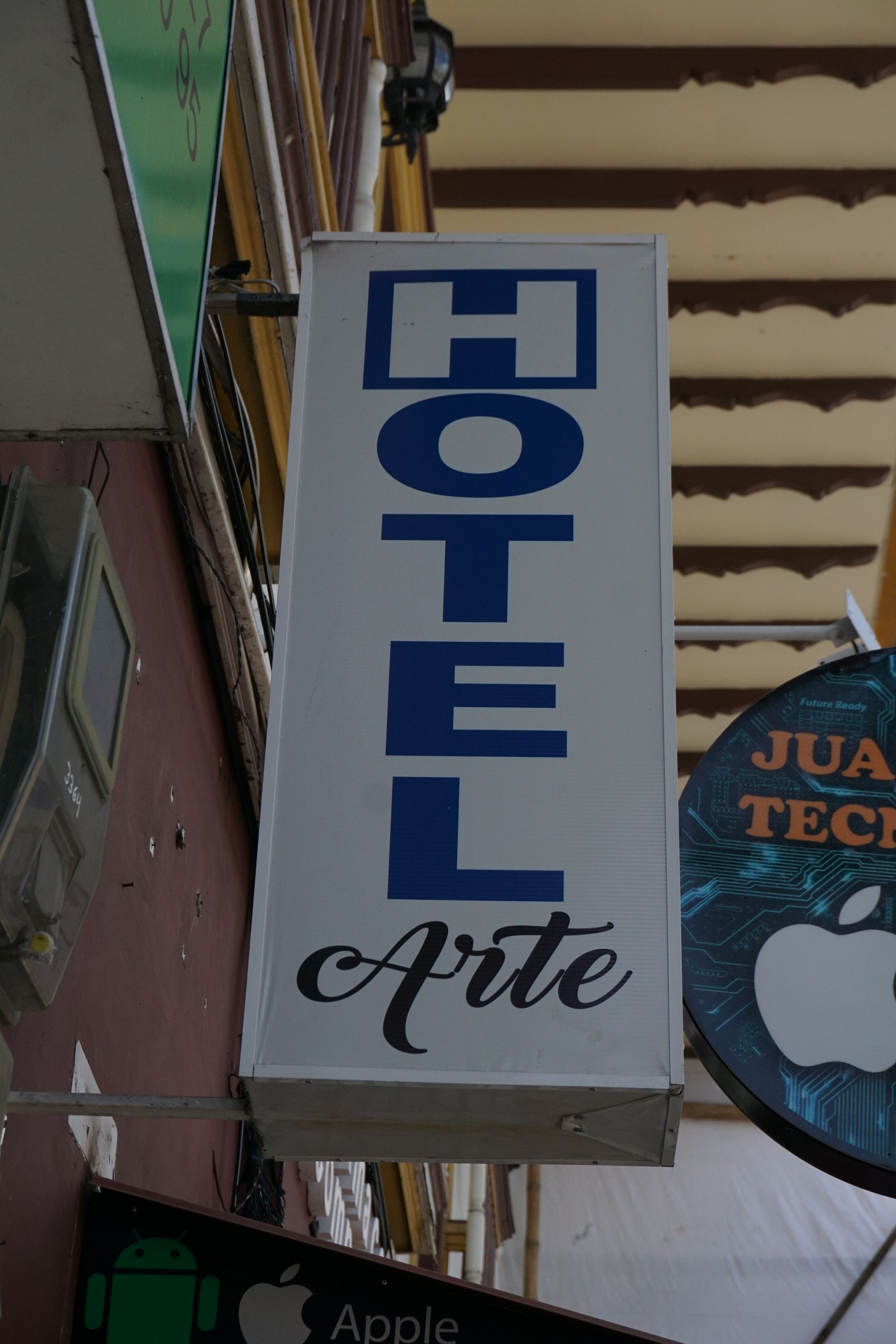 Un letrero de hotel con el nombre 'Hotel Arte' en letras azules grandes sobre un fondo blanco.